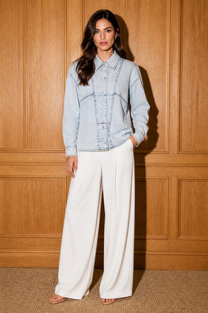 The Amara Denim Shirt - Three-quarter pose with white wide-leg trousers