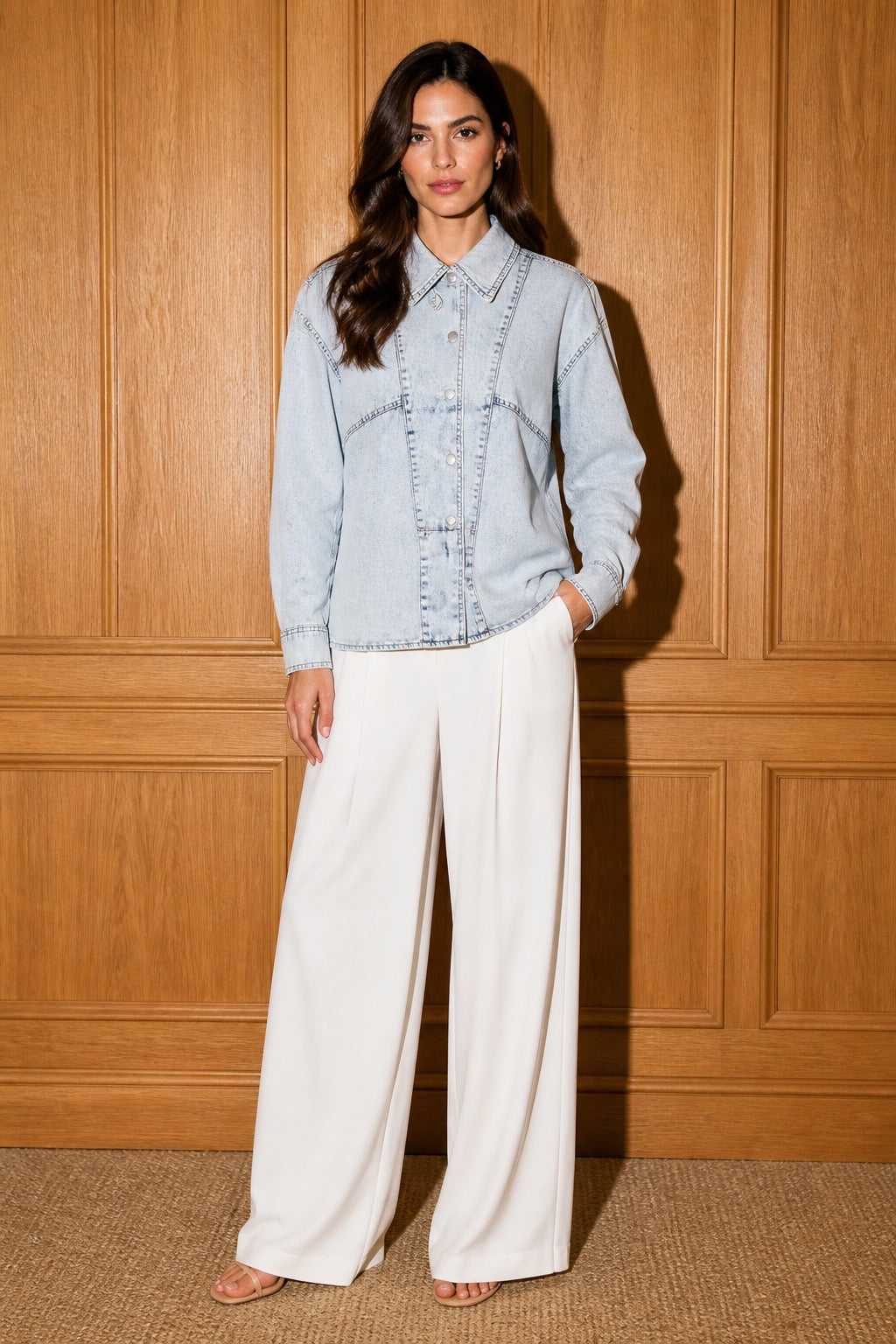 The Amara Denim Shirt - Three-quarter pose with white wide-leg trousers